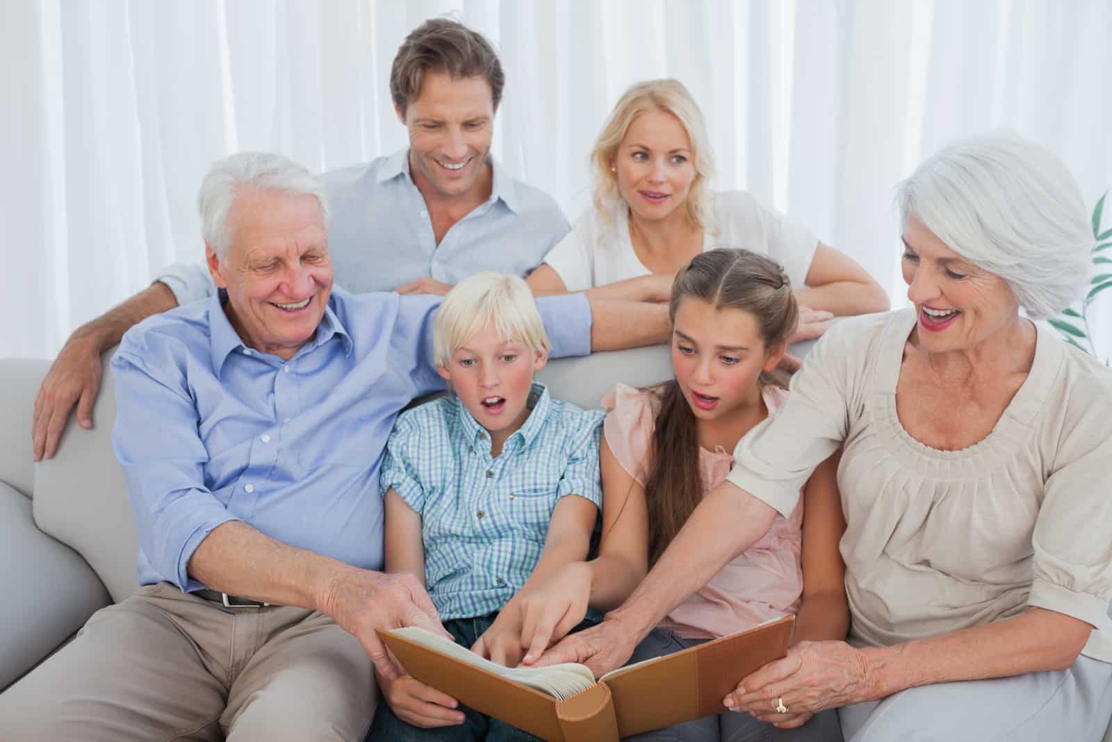 les grands-parents s'assoient avec leurs petits-enfants et regardent des photos