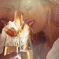 un homme souriant et une femme buvant du vin