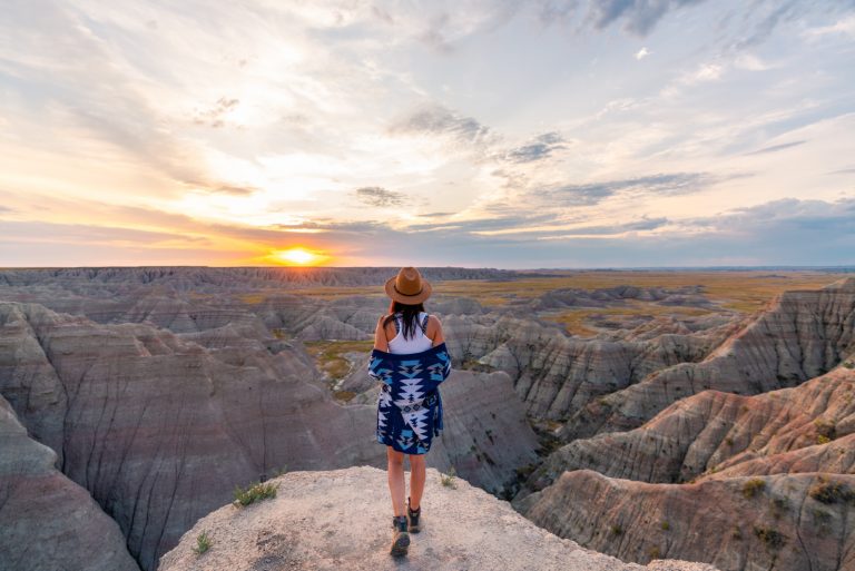 femme avec un chapeau regardant le coucher de soleil