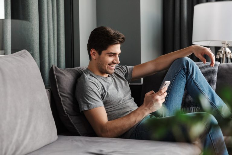 un homme est assis sur le canapé et un bouton du téléphone