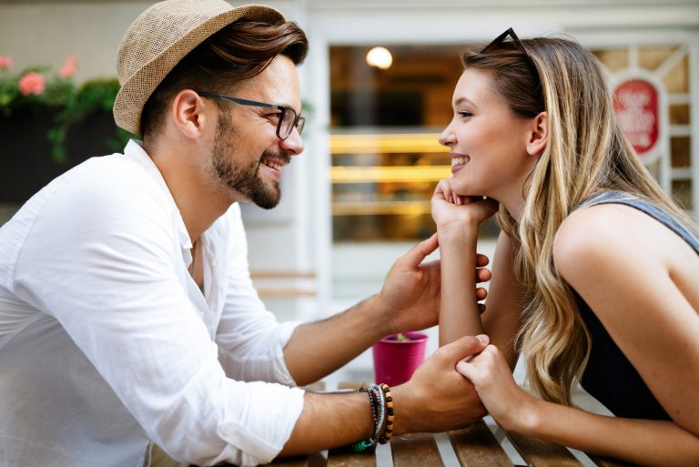 homme tenant la main d'une femme assise à une table