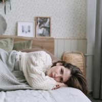 femme triste en chandail blanc allongée sur un lit