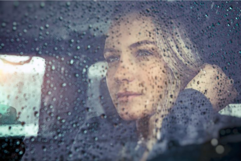 belle femme triste assise dans la voiture par temps de pluie