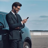 un homme se tient appuyé contre une voiture et un bouton du téléphone