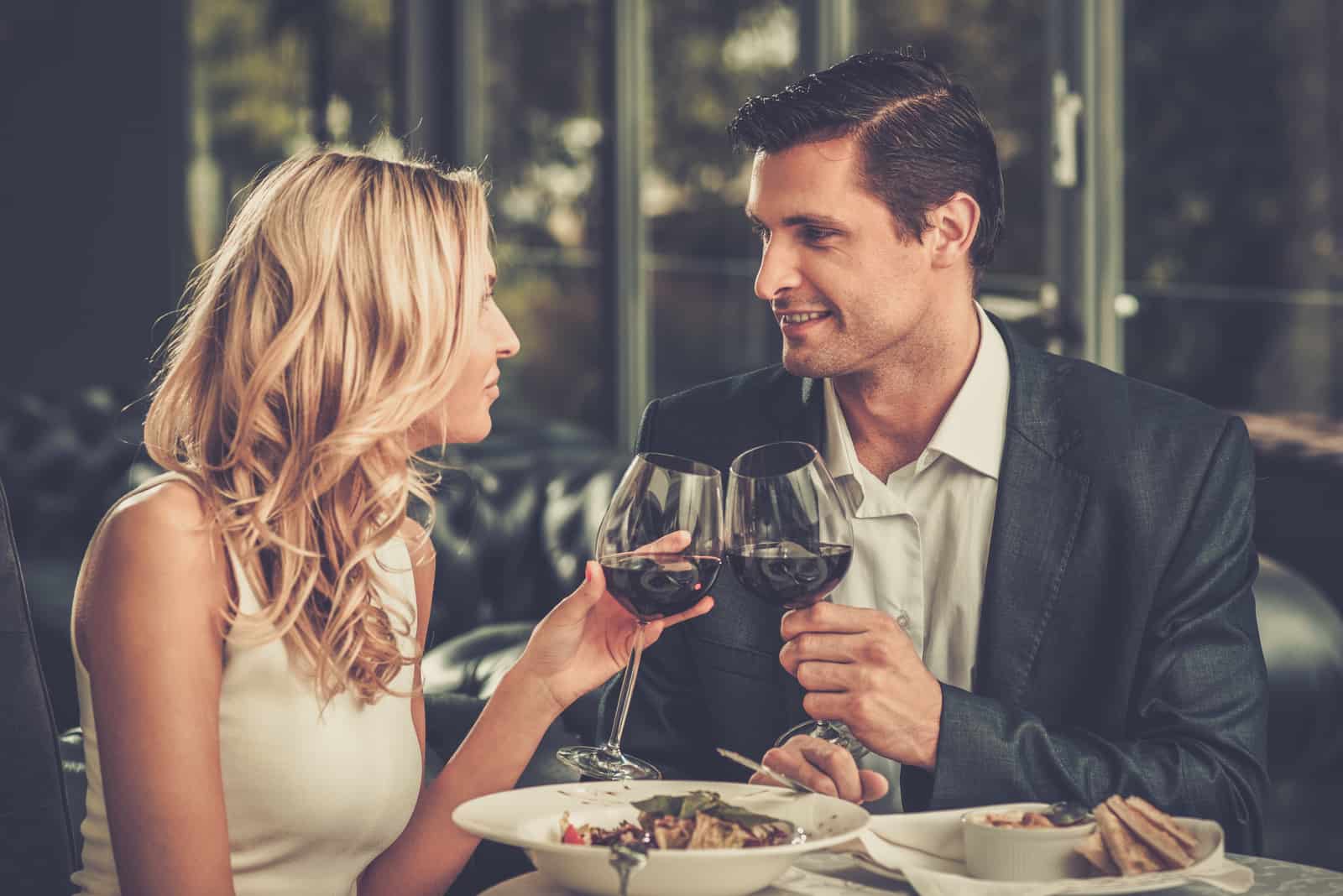 Couple gai dans un restaurant avec des verres de vin rouge