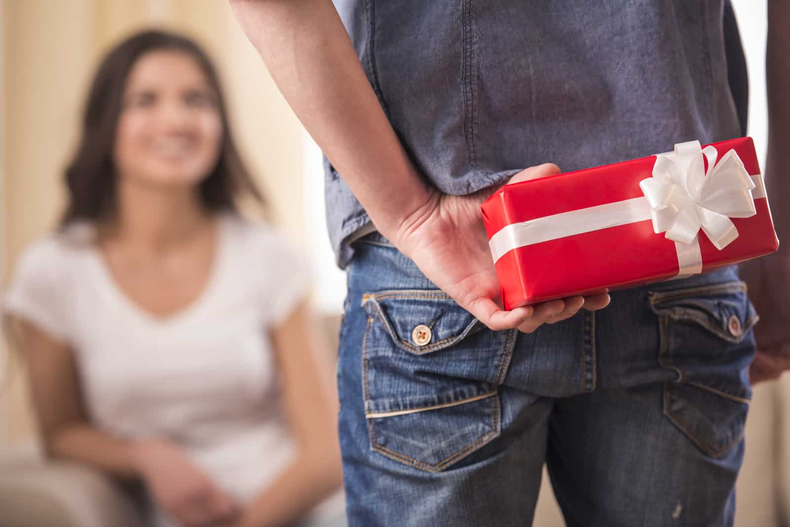 Guy tient un cadeau derrière lui et essaie de surprendre sa petite amie