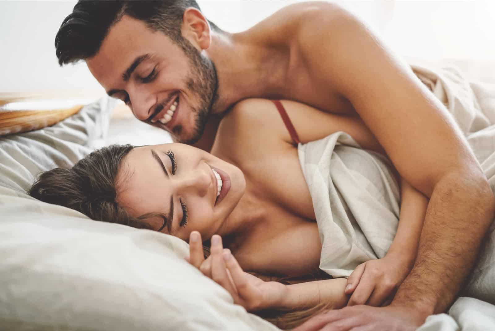 Heureux couple s'amusant sur le lit sous une couverture