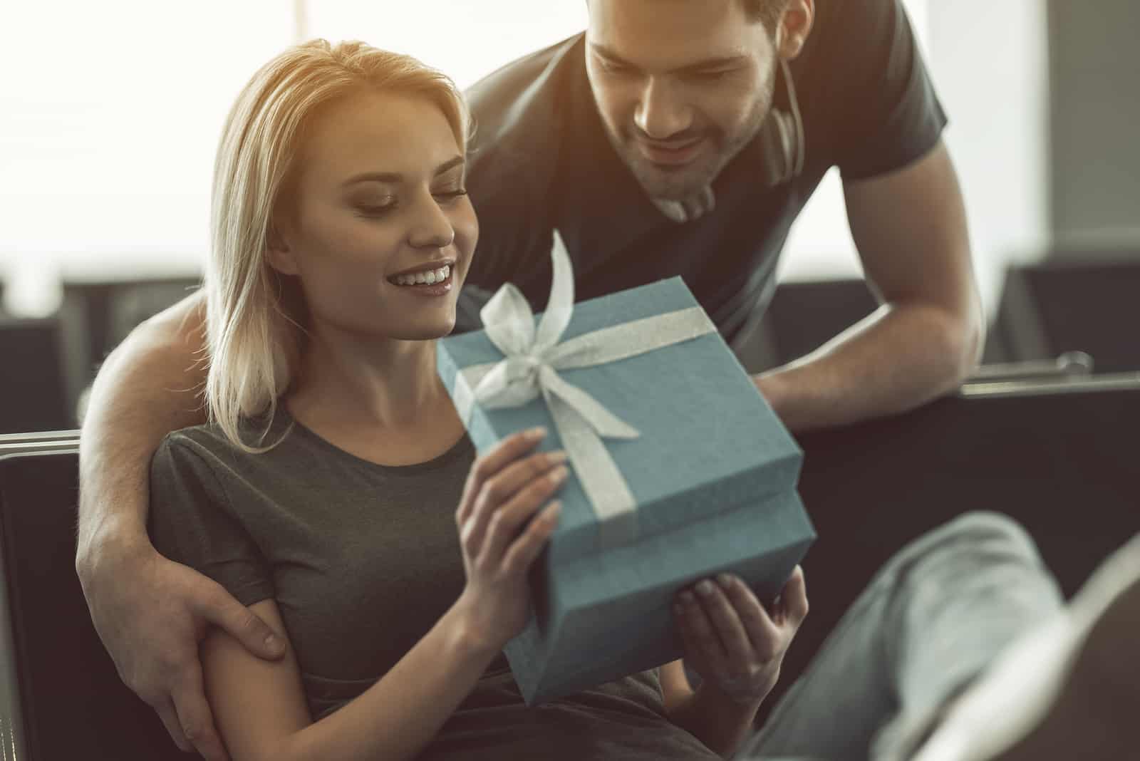 Homme sortant donnant un cadeau pour une femme souriante