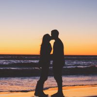 homme et femme s'embrassant sur une plage au coucher du soleil