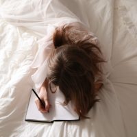 femme écrivant sur un cahier dans un lit