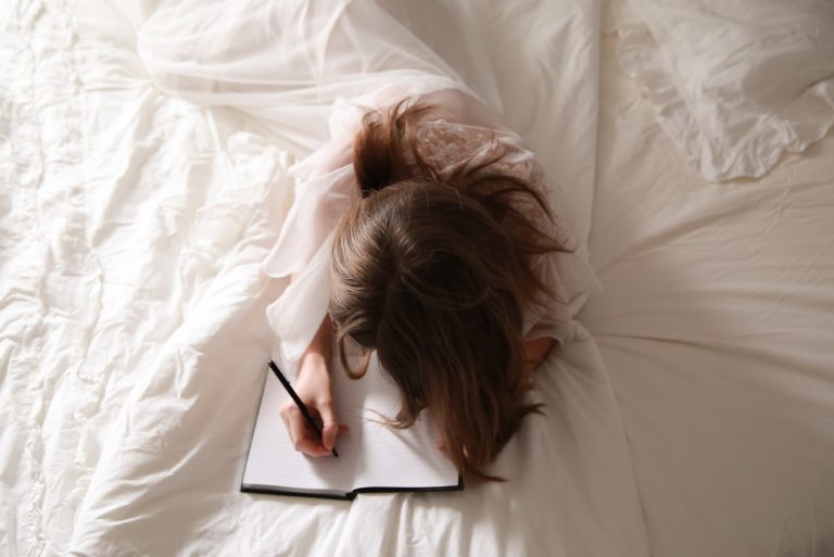 femme écrivant sur un cahier dans un lit