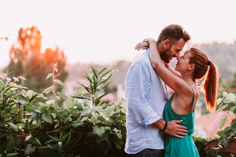 un homme et une femme s'étreignent en se tenant près de plantes