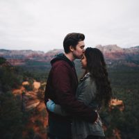 Un homme embrasse le front d'une femme au sommet d'une montagne