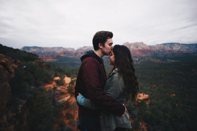 Un homme embrasse le front d'une femme au sommet d'une montagne