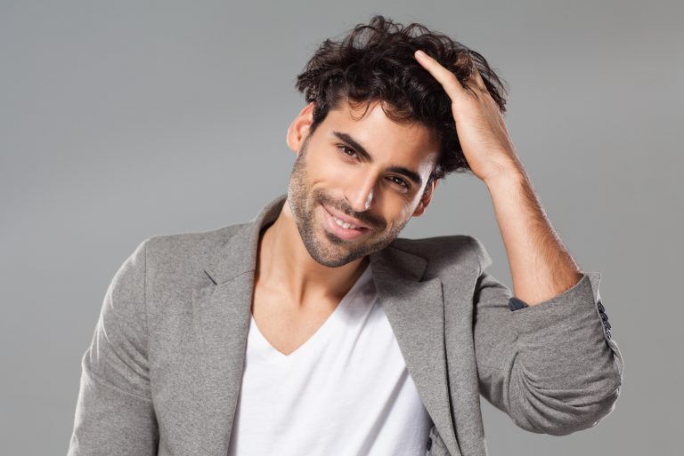un homme souriant touche ses cheveux