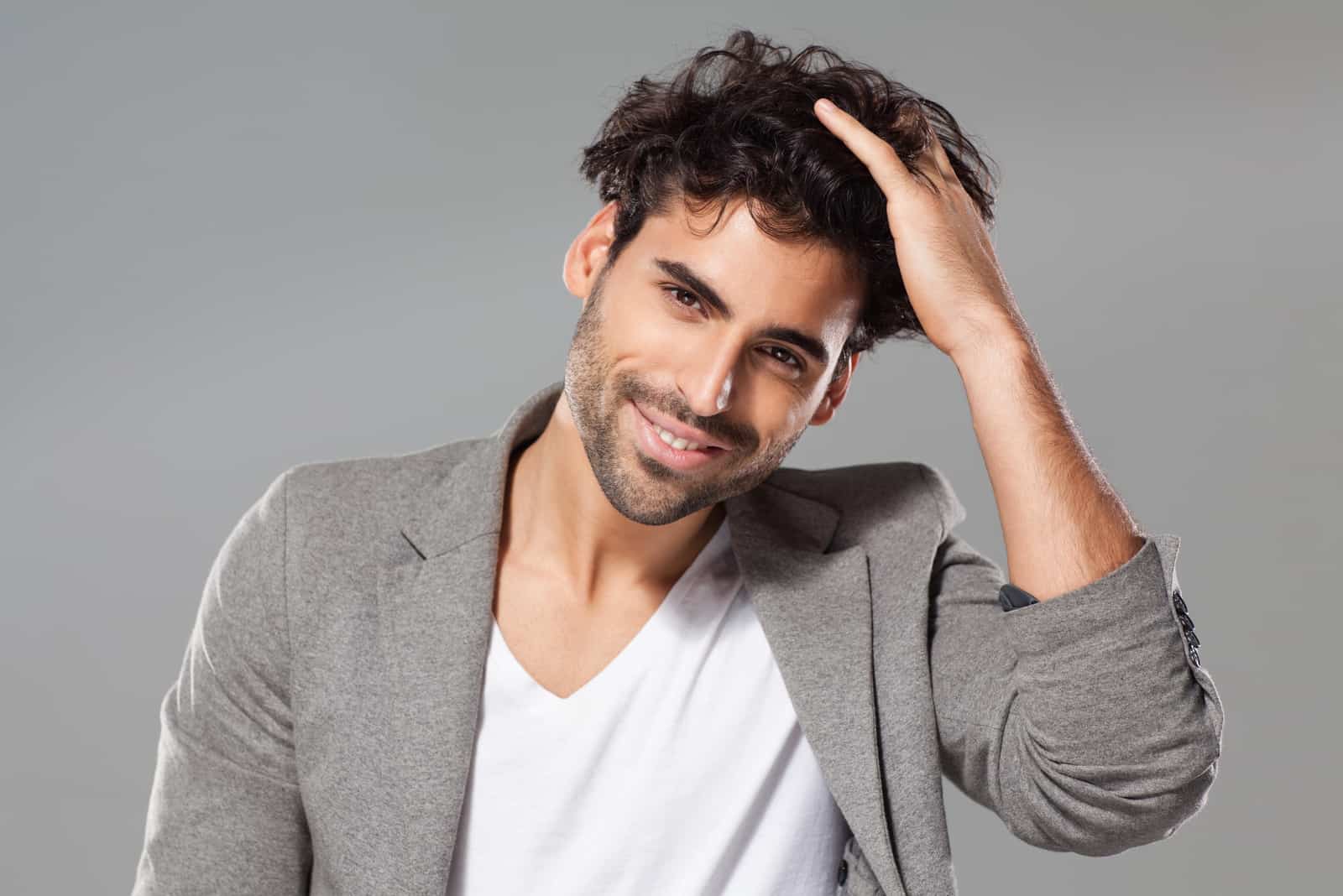 un homme souriant touche ses cheveux