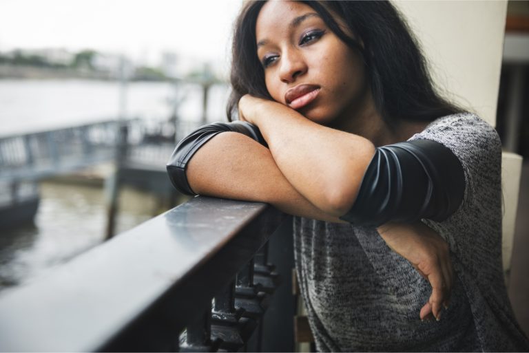 femme triste appuyée sur une barrière