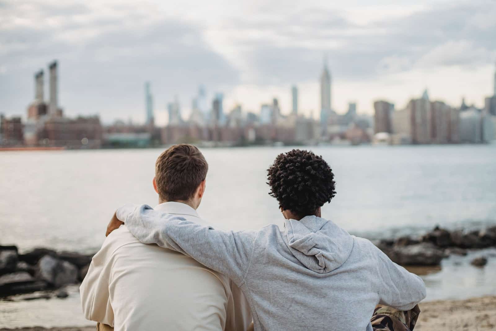 deux amis masculins s'embrassant assis près d'une rivière