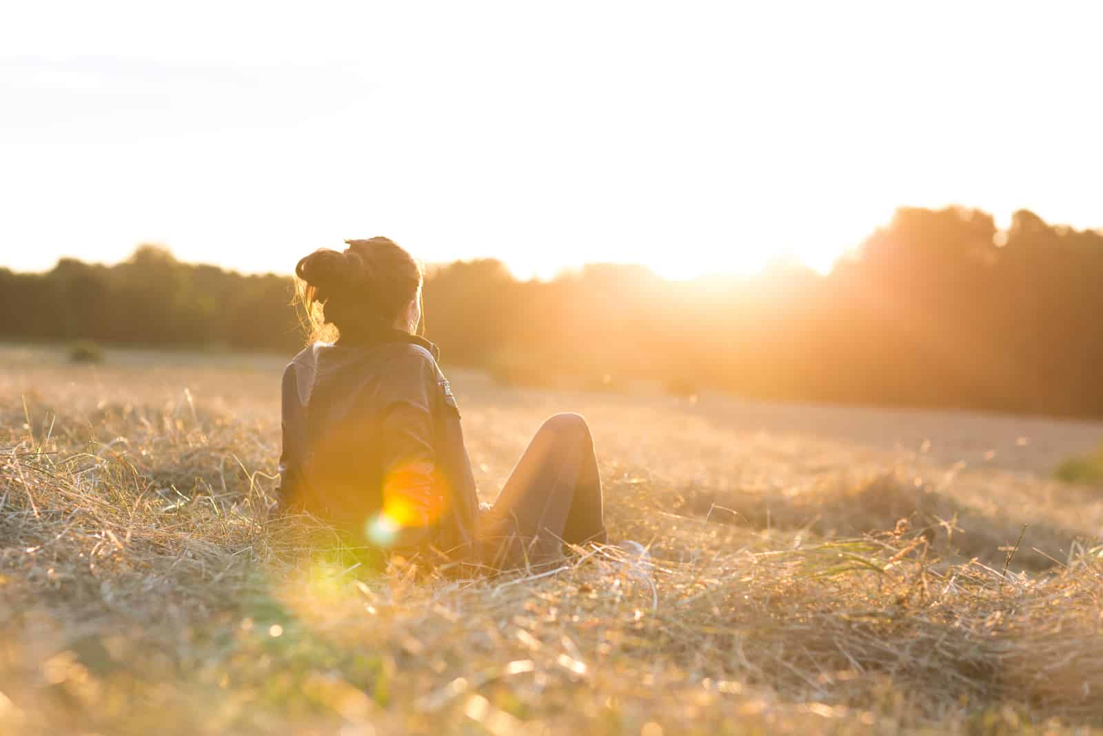 belle jeune femme ou fille sur le pré en regardant le coucher du soleil