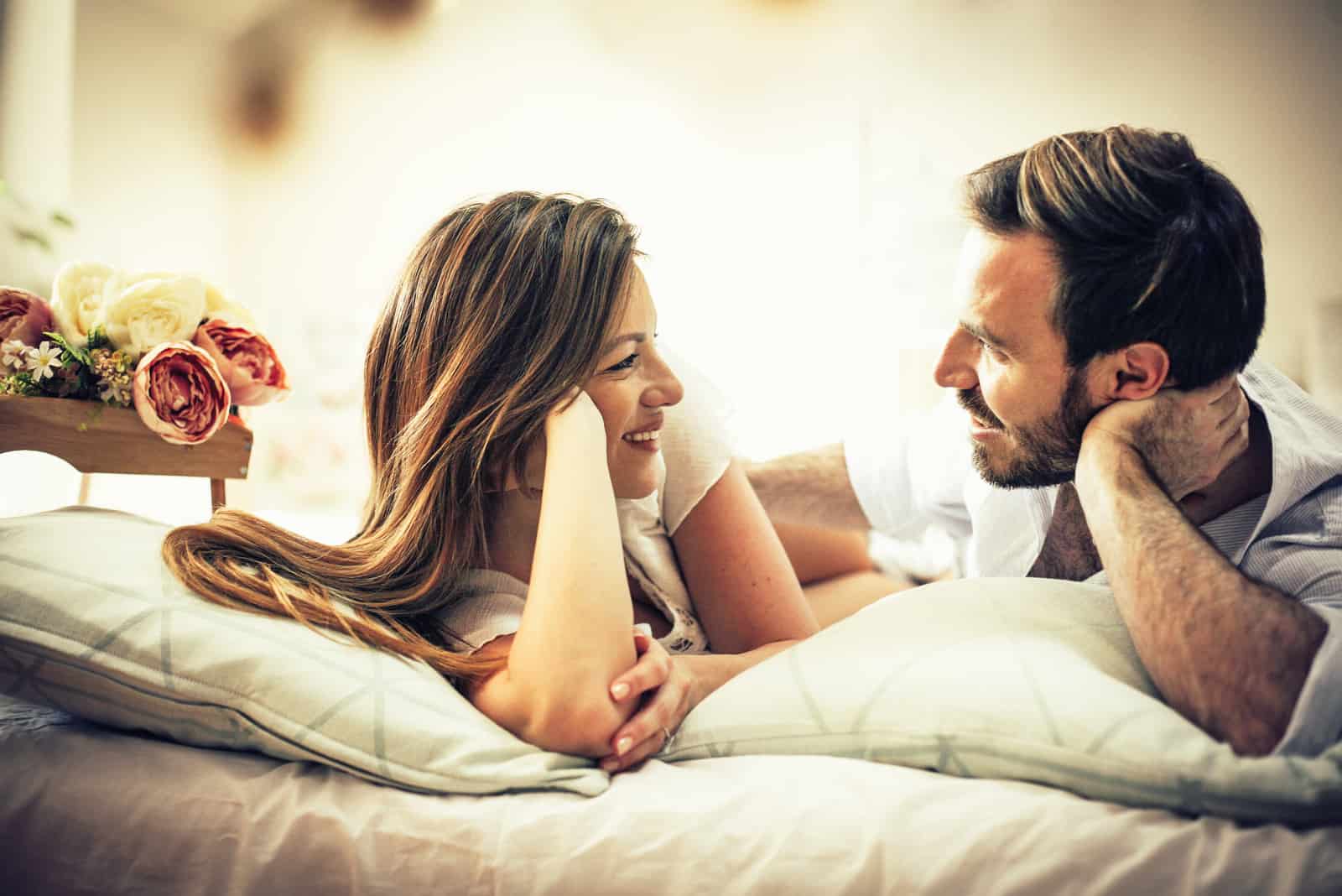 Un homme et une femme discutent en étant allongés sur un lit