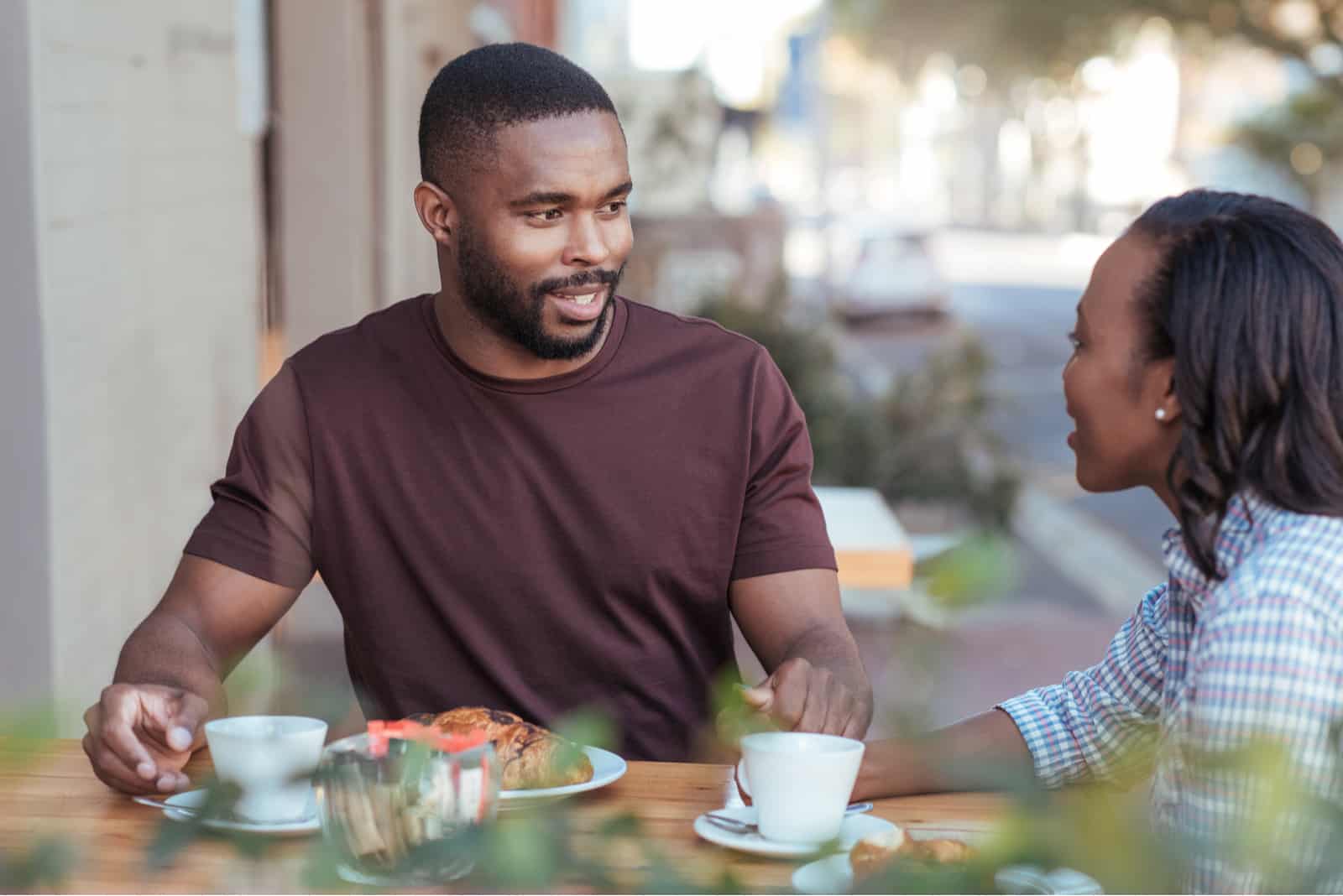 couple assis à une table dans un café-terrasse buvant du café