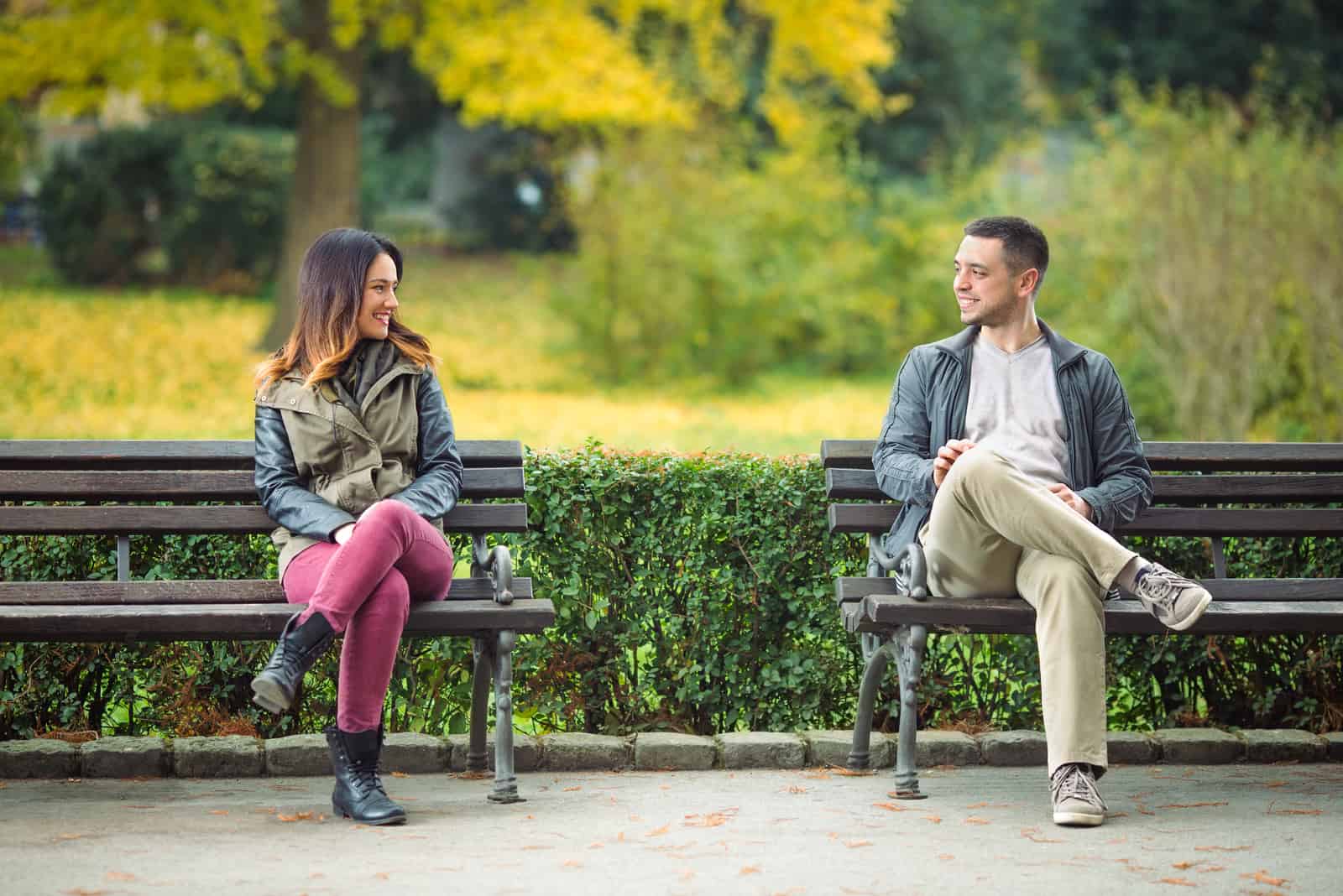 Un homme et une femme se regardent dans les yeux assis sur un banc