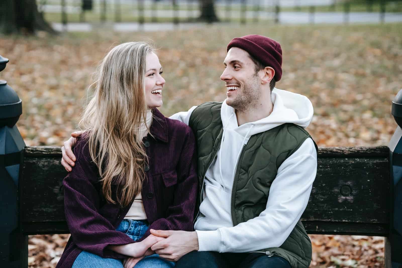 homme et femme souriant assis sur un banc