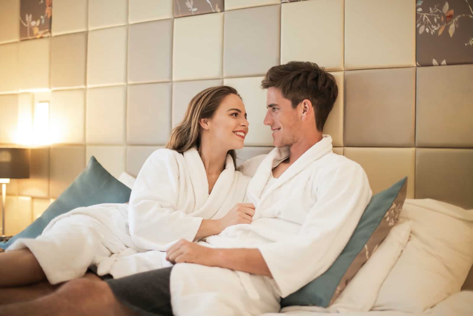homme et femme souriant assis sur un lit