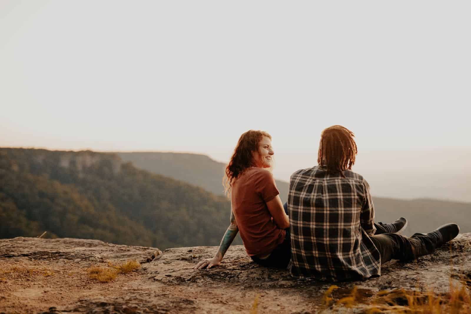 homme et femme parlant assis sur un rocher