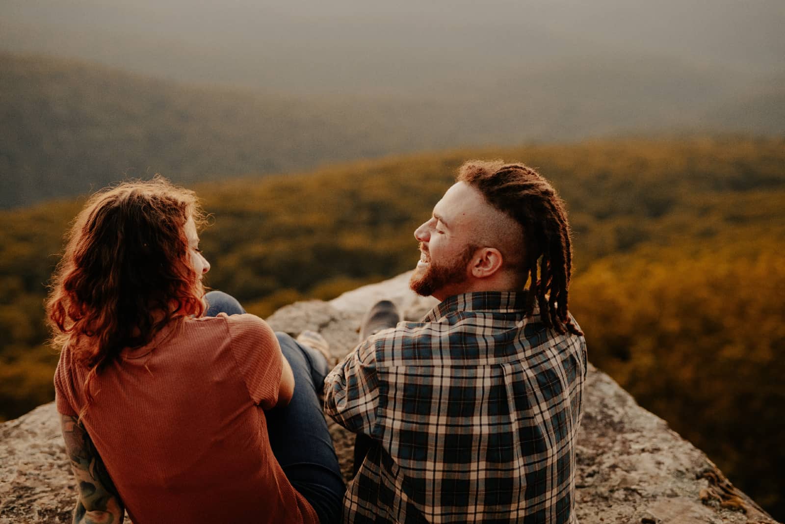 homme et femme souriant assis sur un rocher