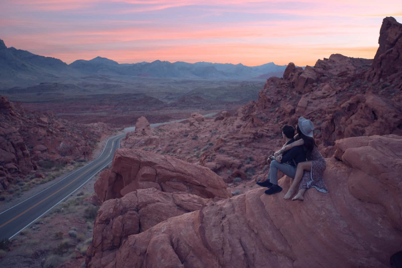 homme et femme assis sur un rocher pendant le coucher du soleil
