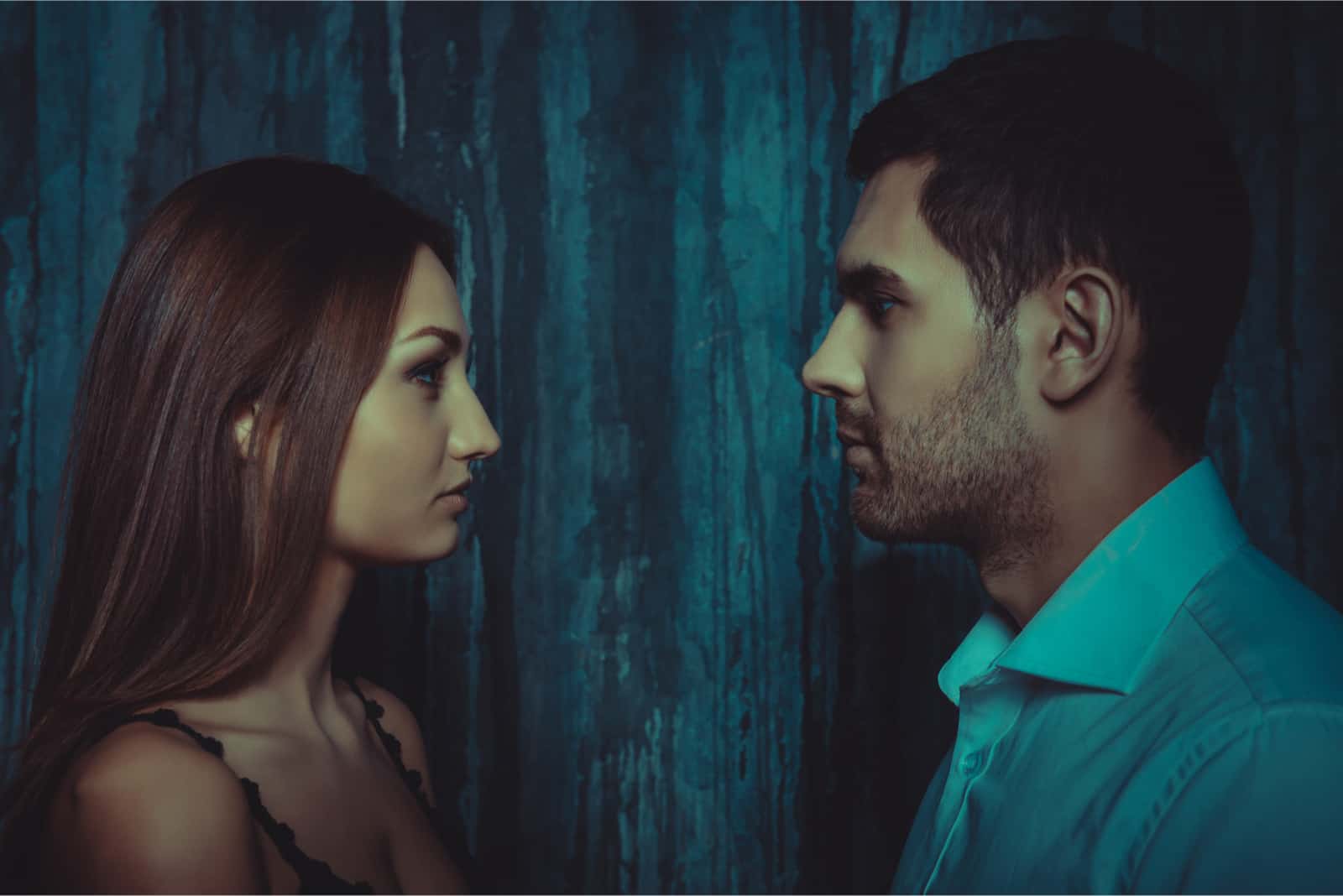 Un homme et une femme se regardent dans les yeux en se tenant près d'un mur