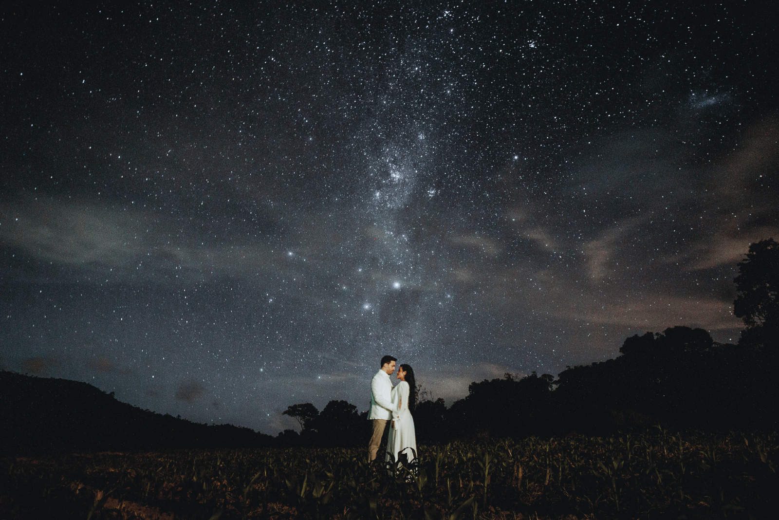 homme et femme debout sur un champ la nuit