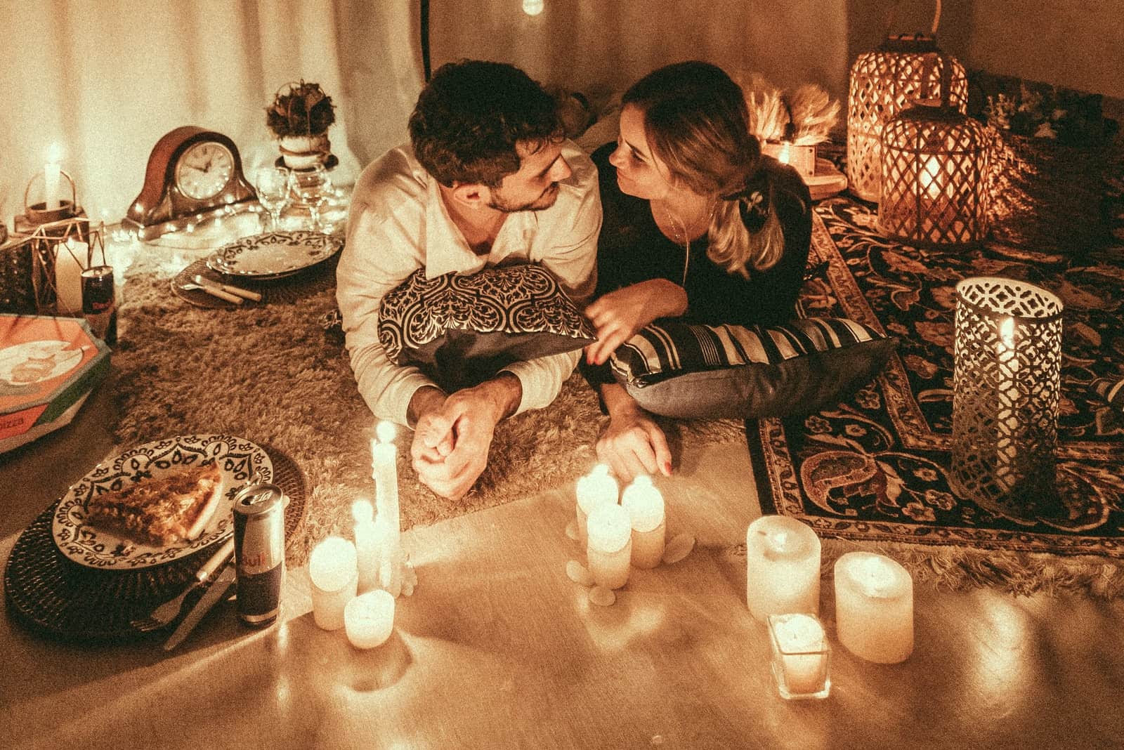 Un homme et une femme se regardent dans les yeux alors qu'ils sont allongés près de bougies