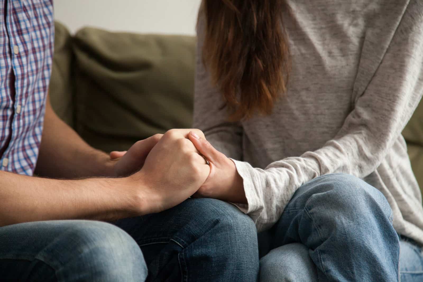 homme et femme se tenant la main assis sur un canapé