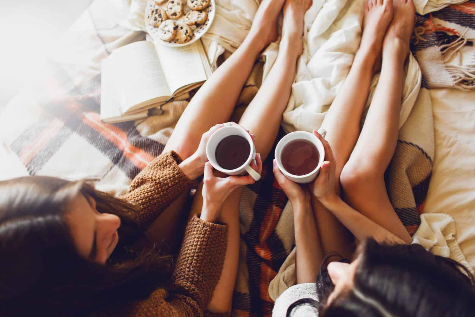 deux soeurs sur le lit avec de vieux livres et une tasse de thé dans les mains