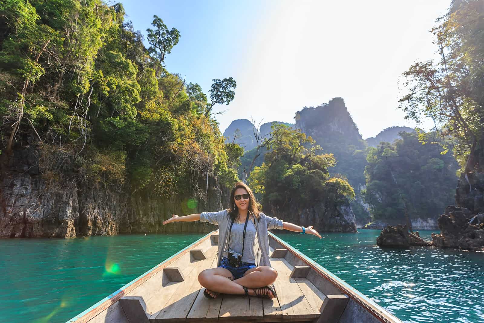 femme heureuse avec des lunettes de soleil assise sur un bateau