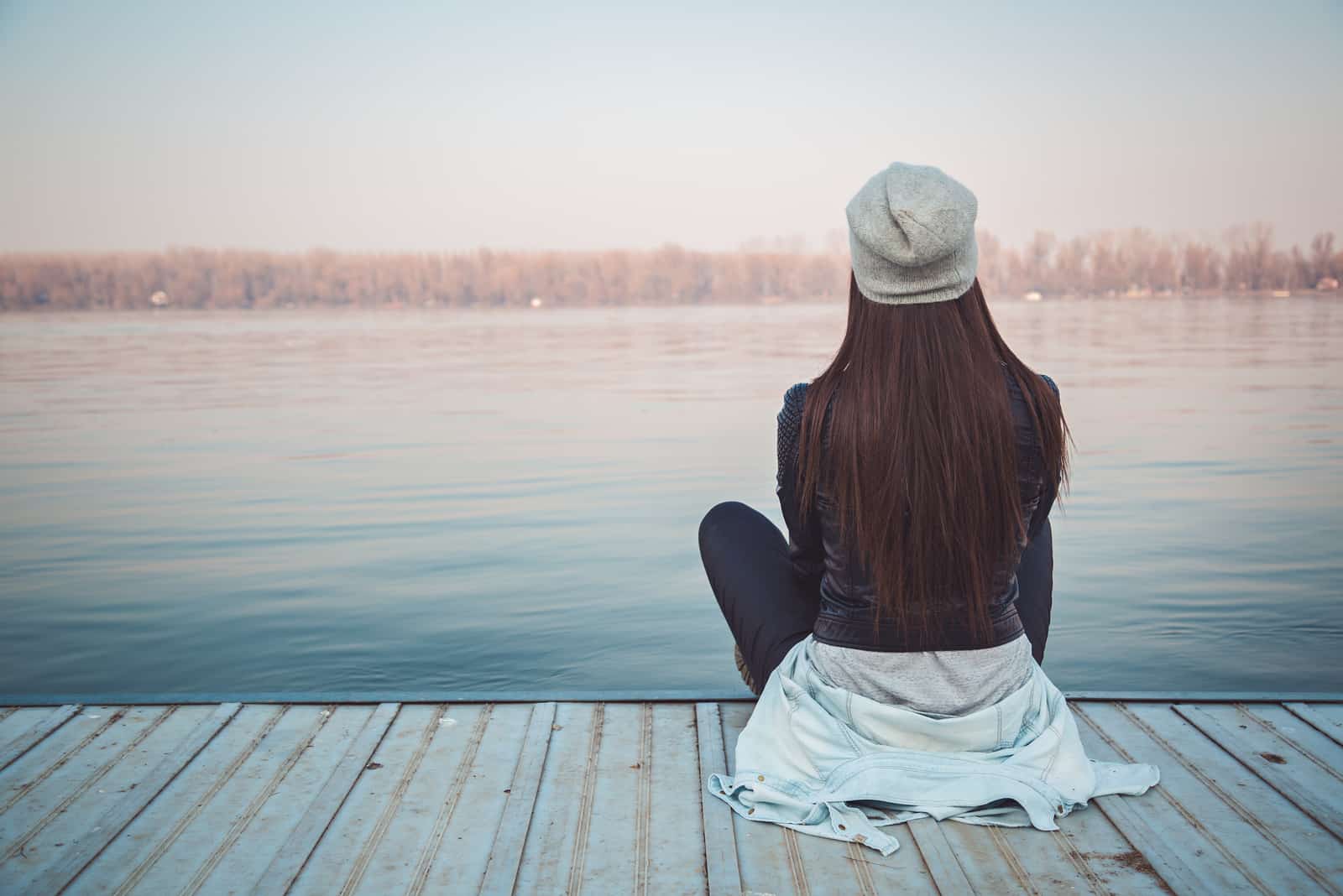 femme assise sur un quai regardant l'eau