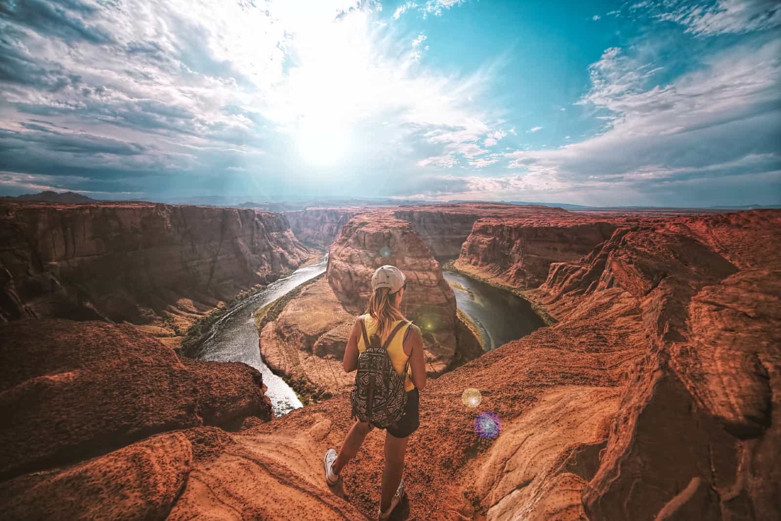 femme avec un sac à dos au sommet d'un canyon