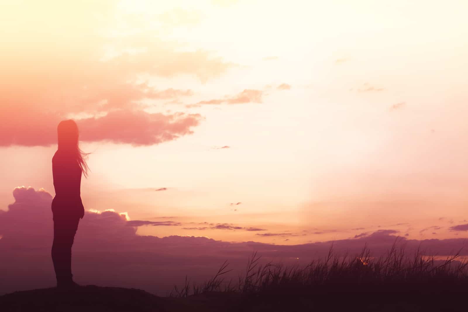 femme debout seule sur le terrain pendant le beau coucher de soleil