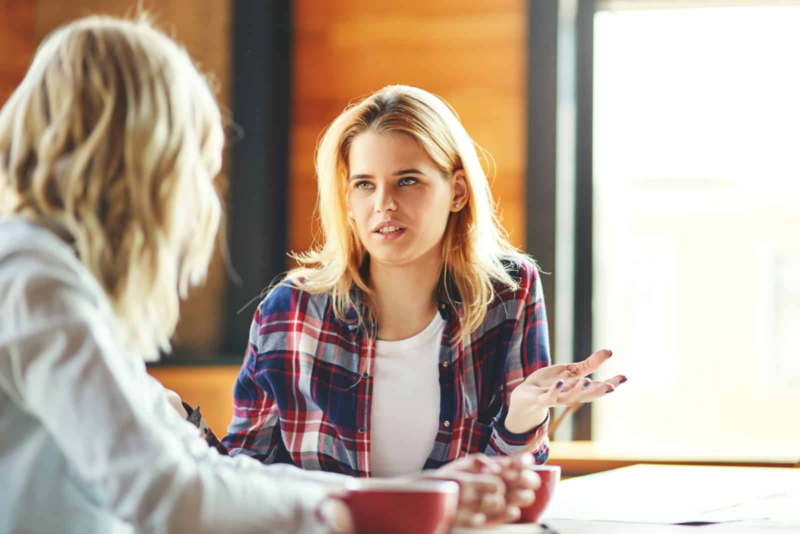 femme parlant à une autre femme assise dans un café