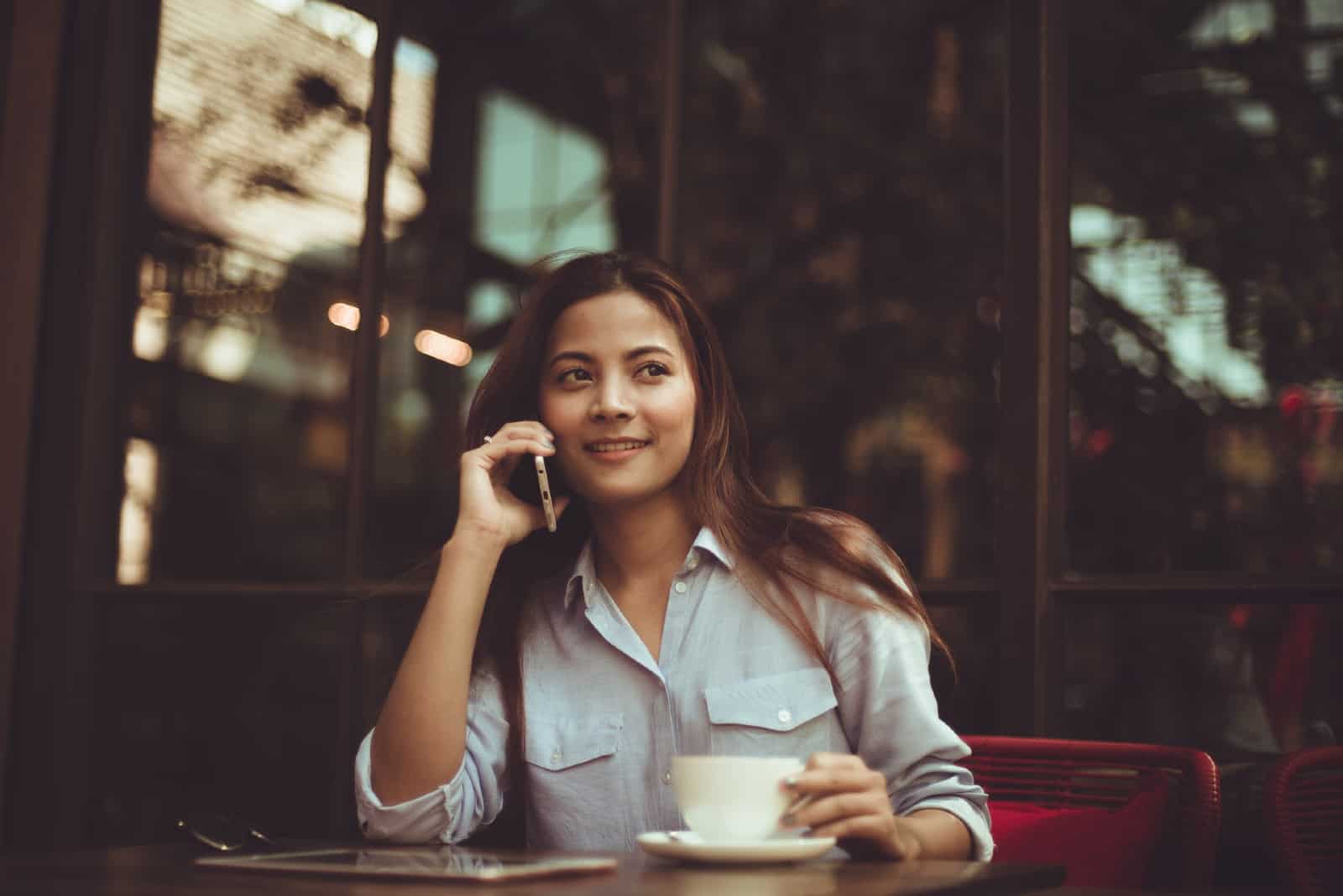 femme parlant au téléphone assise dans un café