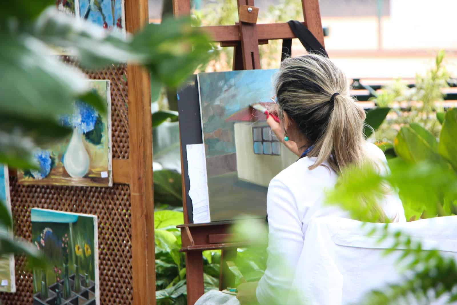 femme peignant sur une toile dans un jardin