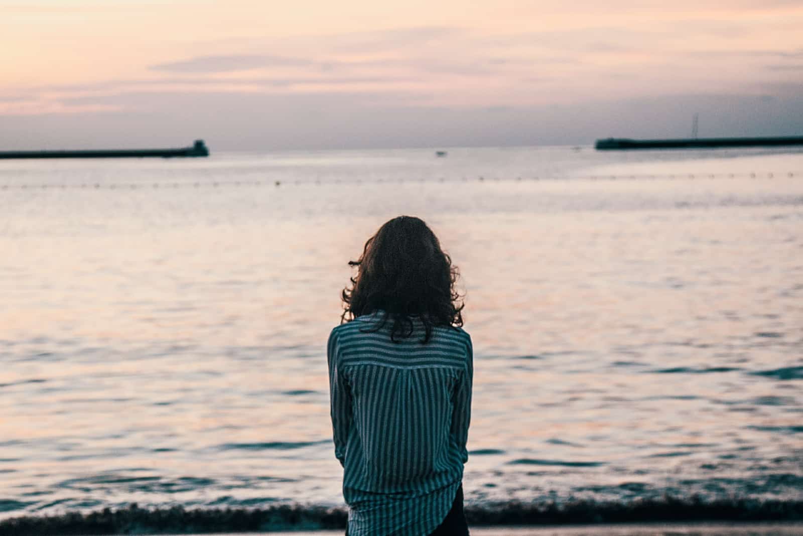femme en chemise rayée regardant la mer