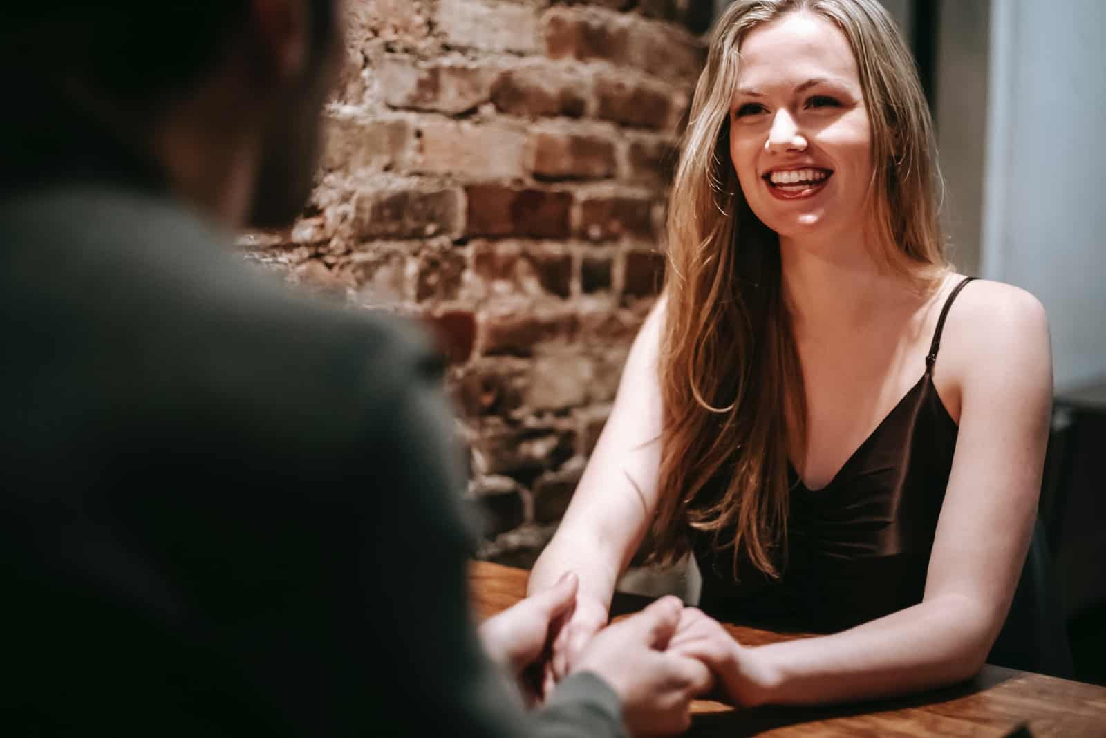 femme heureuse regardant un homme assis à une table