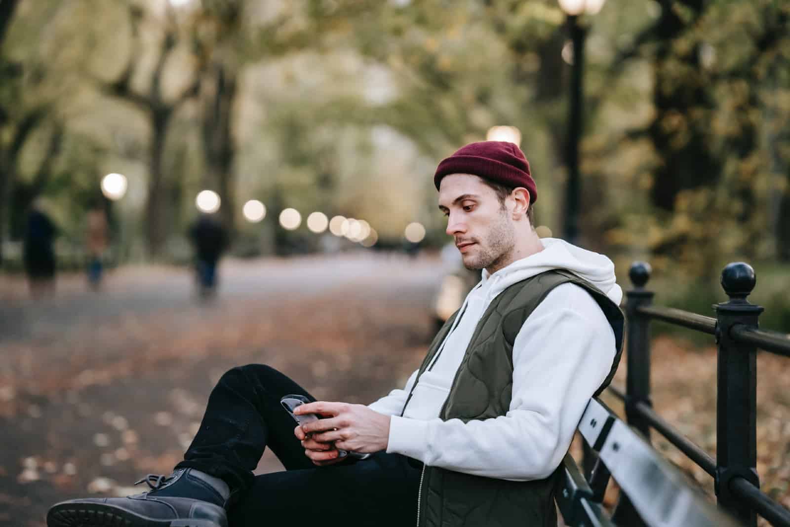Un homme utilise un smartphone alors qu'il est assis sur un banc