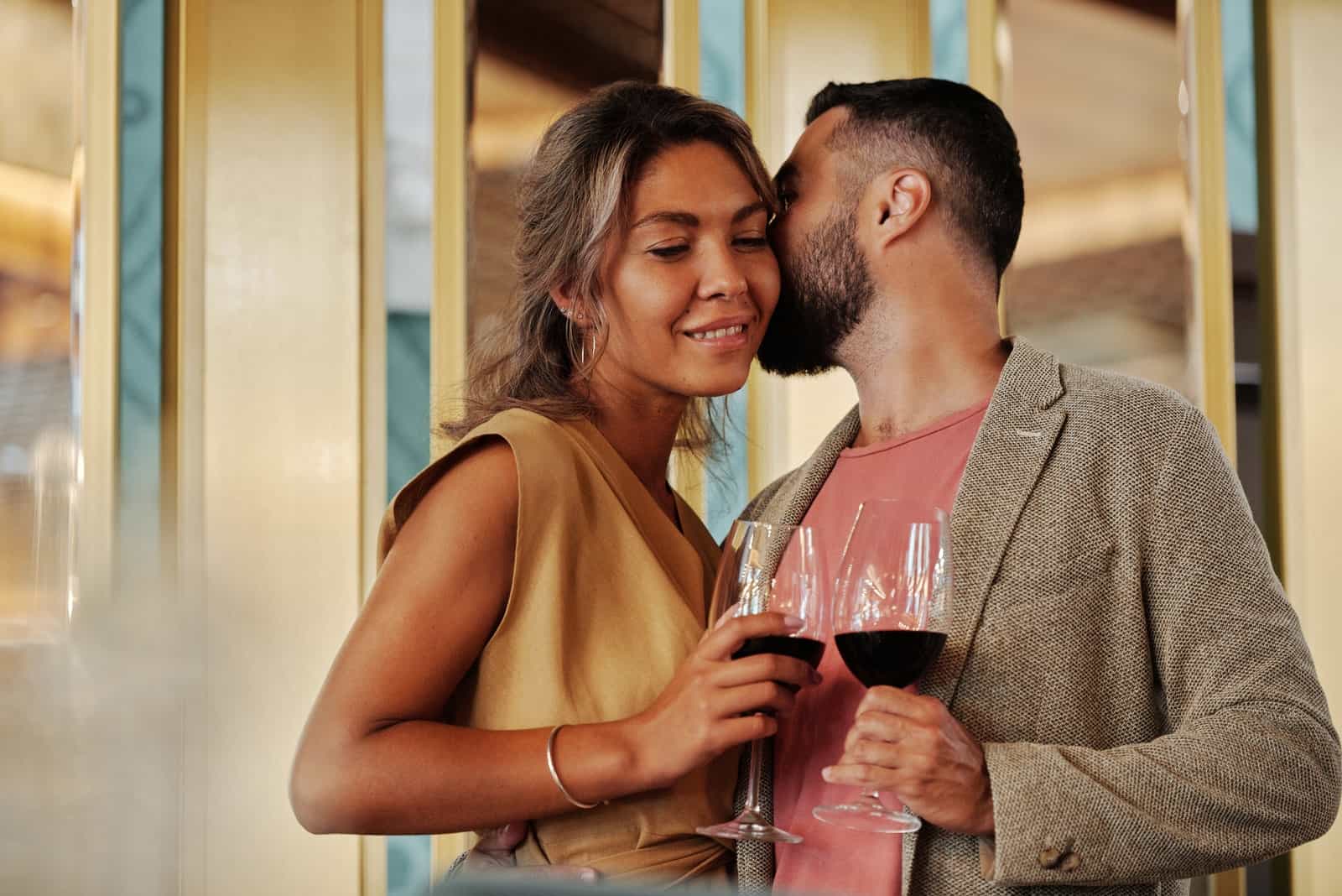 homme embrassant une femme en tenant un verre de vin