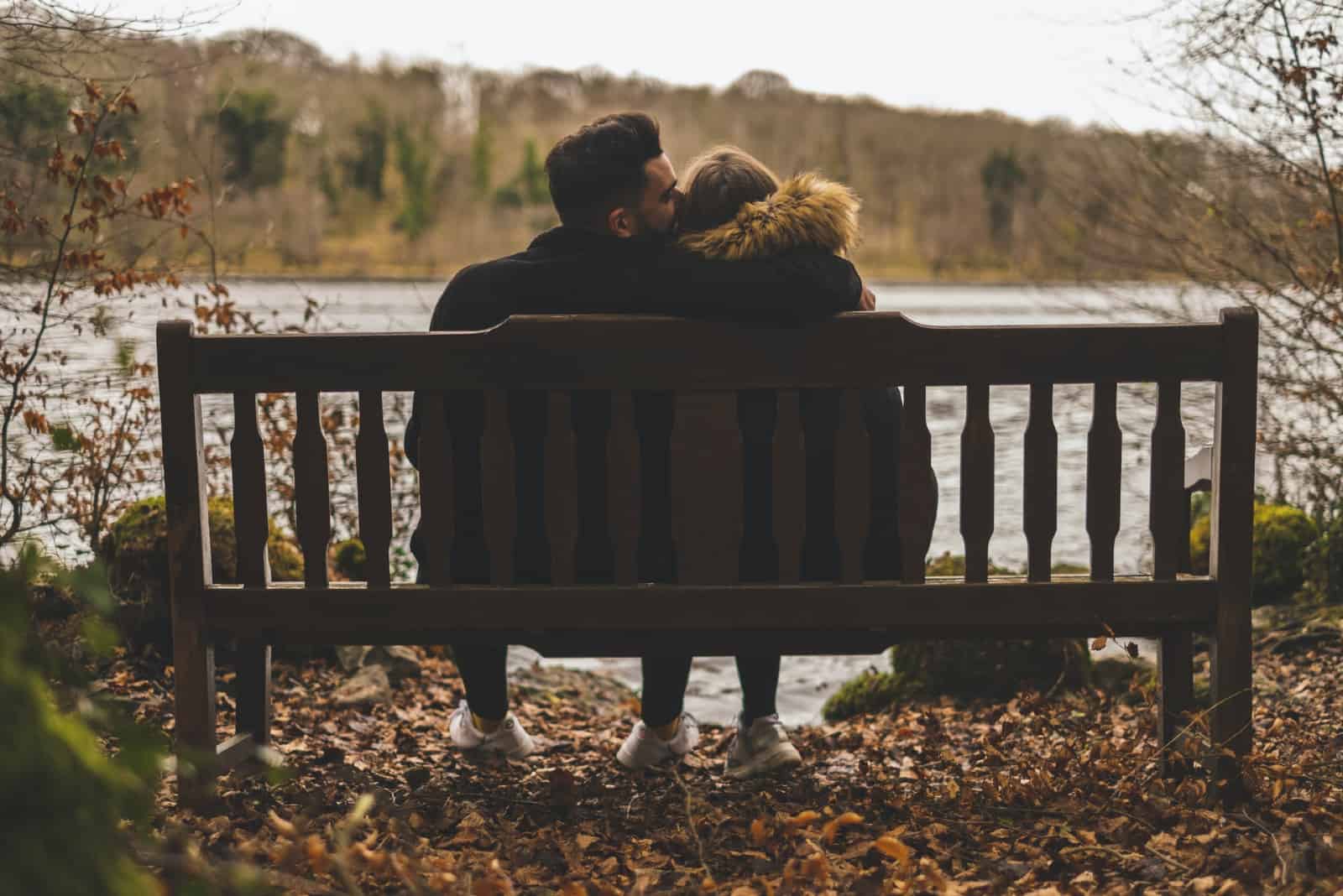 homme embrassant une femme assise sur un banc