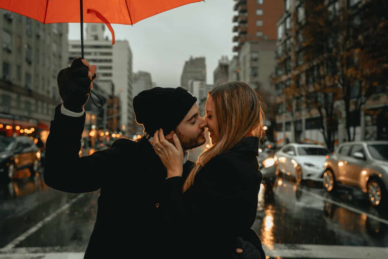 homme tenant un parapluie tout en embrassant une femme