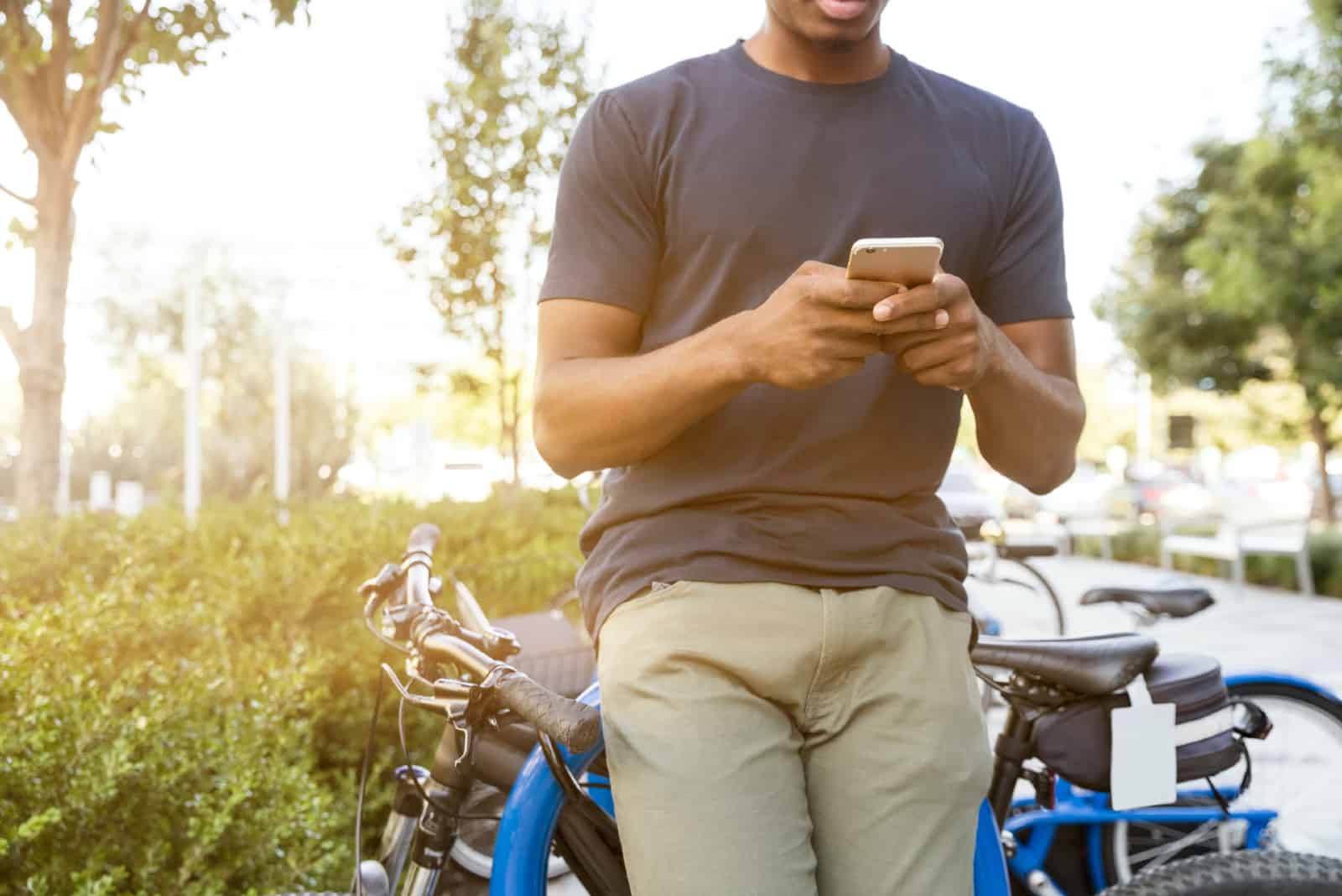 Un homme utilise un smartphone en s'appuyant sur une moto